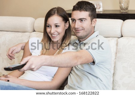 happy man watching tv with his girlfriend sitting