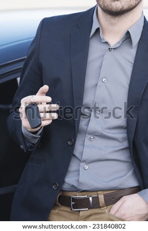 man standing out of his car with key