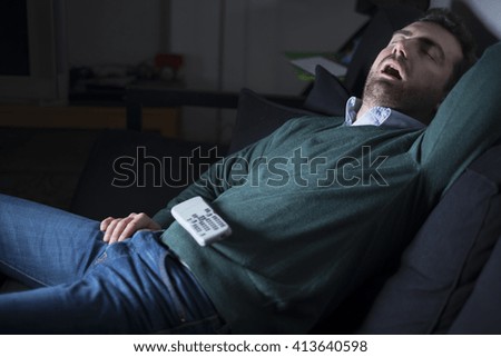 Man sleeping and snoring in front of television on the couch