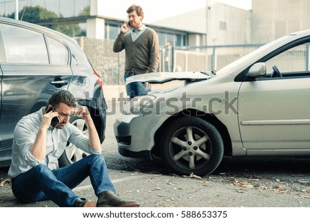 Two men calling car help assistance after an accident