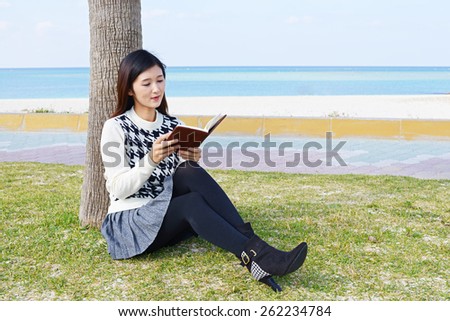 Woman reading a book by the ocean