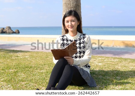 Woman reading a book by the ocean