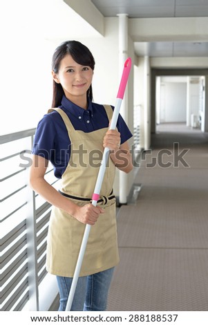 young woman with a broom sweeping the entrance