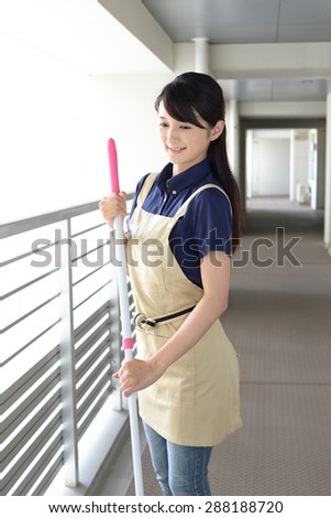 young woman with a broom sweeping the entrance