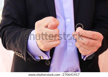 A man in a business suit shows figo, on the other hand shows a wedding ring. The concept of the man does not want to marry.