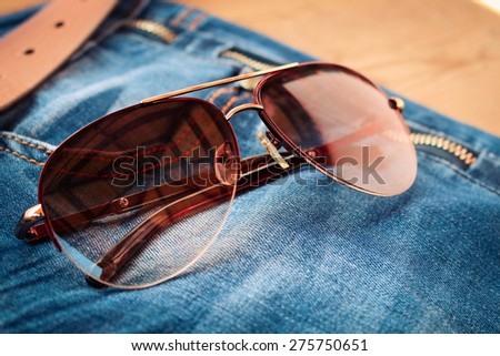 Sunglasses on jeans background. Toned image.