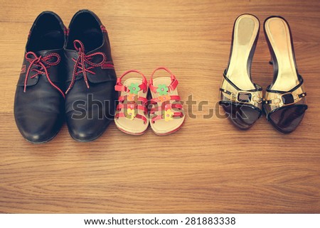 Three pairs of shoes: men, women and children. Baby sandals stand next to men\'s  shoes. concept of the child is friends with his father. Idea parents divorced, child remained with father. Toned image