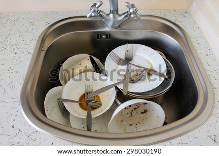 Dirty dishes: plates, cup, forks, spoons in the sink