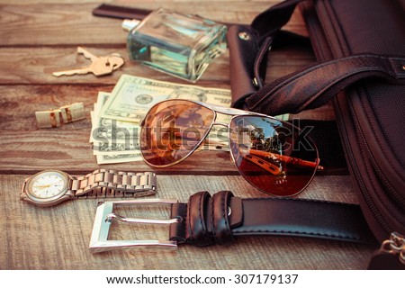 Men accessories: sunglasses,  bag, money, wrist watch, cufflinks, comb, strap, keys, perfume on the old wood background. Toned image.