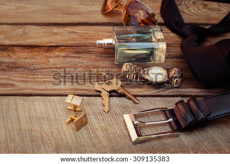 Men accessories: sunglasses, bag,  wrist watch, cufflinks, comb, strap, keys, tie, perfume on the old wood background. Toned image.