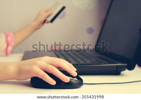 Close up of female hand on computer mouse and holding a credit  card. The concept of online shopping.