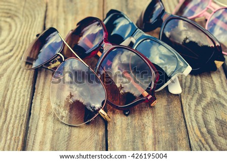 Different sunglasses on wooden background. Toned image.