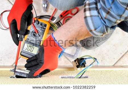 Electrician technician at work fixes the support screw in a residential electrical installation