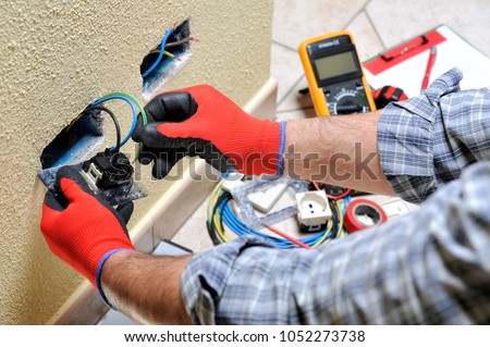 Electrician technician at work sticks the cable between the clamps of a socket in a residential electrical installation