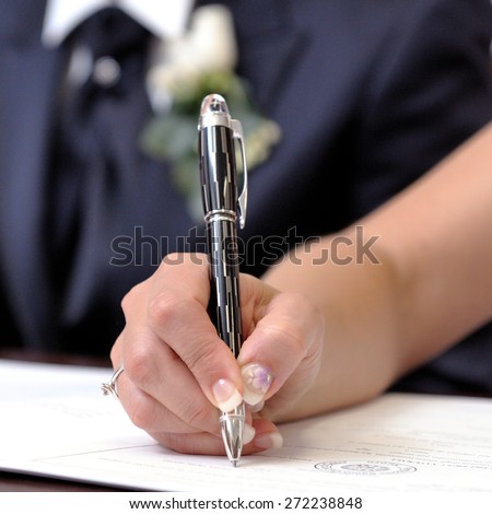Bride signing the marriage certificate after the wedding