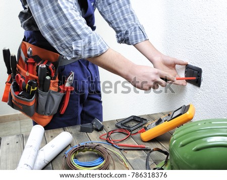 Young electrician at work on switches and sockets of a residential electrical installation.