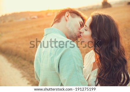 Young couple in love outdoor.d.Couple hugging.Young beautiful couple in love staying and kissing on the field on sunset. Soft sunny colors.