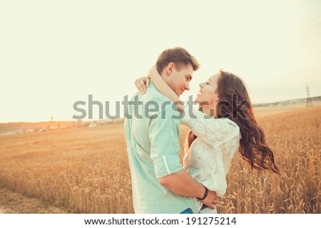 Young couple in love outdoor.in summer in field.Couple hugging.Young beautiful couple in love staying and kissing on the field on sunset. Soft sunny colors.