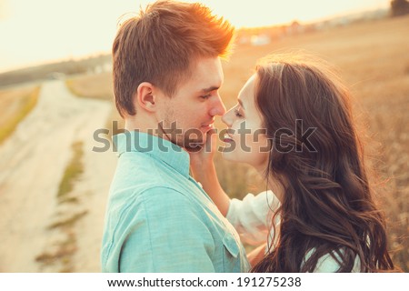 Young couple in love outdoor.d.Couple hugging.Young beautiful couple in love staying and kissing on the field on sunset. Soft sunny colors.