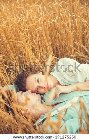 Young couple in love outdoor.in summer in field.Couple hugging.Young beautiful couple in love staying and kissing on the field on sunset. Soft sunny colors. Beautiful couple lying on the glass