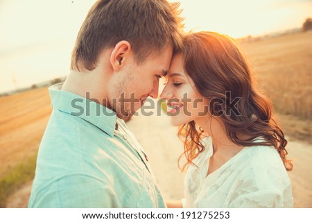 Young couple in love outdoor.in summer in field.Couple hugging.Young beautiful couple in love staying and kissing on the field on sunset. Soft sunny colors.