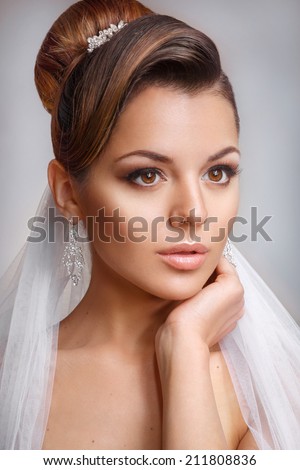 Portrait of the bride with big beautiful eyes on gray background.