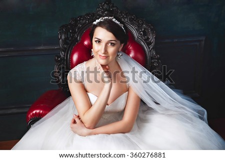 Young bride is sitting in an armchair.Beautiful Bride Portrait wedding makeup, wedding hairstyle, Wedding dress. Wedding decoration. soft selective focus. gorgeous young bride at interior