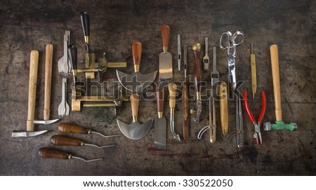Leather goods craftsman\'s tools on a dirty work bench