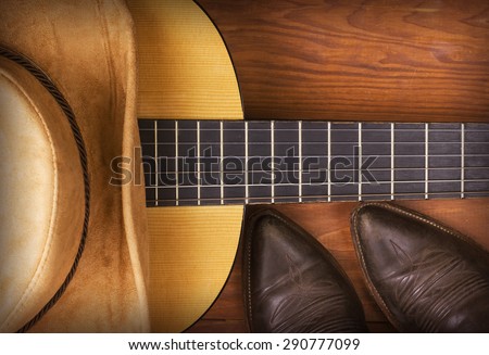 American Country music with guitar and cowboy shoes on wood background