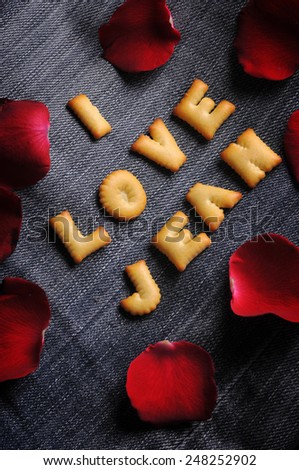 Cookies ABC in the form of word I LOVE JEAN alphabet with red rose petal on old jean background, Valentines day