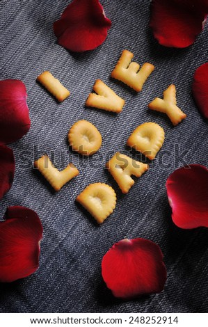 Cookies ABC in the form of word I LOVE DADY alphabet with red rose petal on old jean background, Valentines day