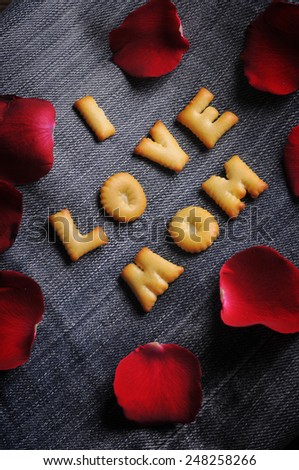 Cookies ABC in the form of word I LOVE MOM alphabet with red rose petal on old jean background, Valentines day