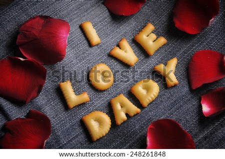 Cookies ABC in the form of word I LOVE DADY alphabet with red rose petal on old jean background, Valentines day