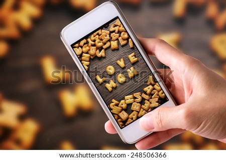 using mobile phones to take photos of Cookies ABC in the form of word LOVE MOM alphabet on old wood background, Valentines day