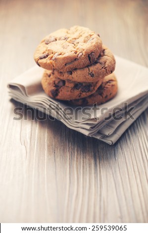 Chocolate cookies on white napkin on wooden background. Chocolate chip cookies shot on colored cloth, closeup.