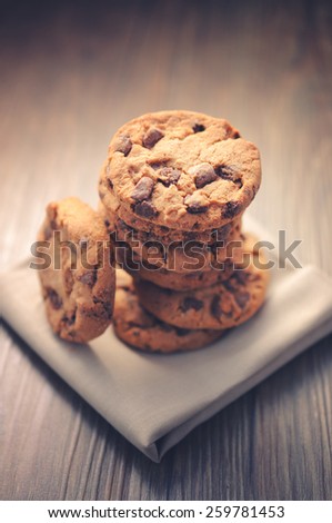 Chocolate cookies on white napkin on wooden background. Chocolate chip cookies shot on colored cloth, closeup.