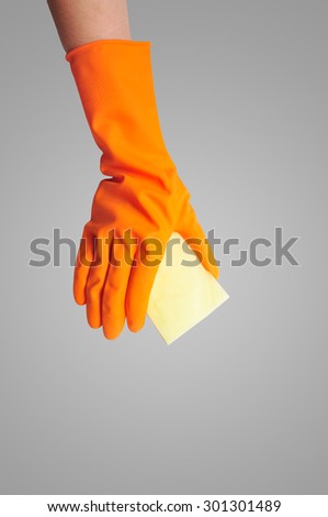 Hand in orange rubber glove with sponge isolated on gray background. cleaning