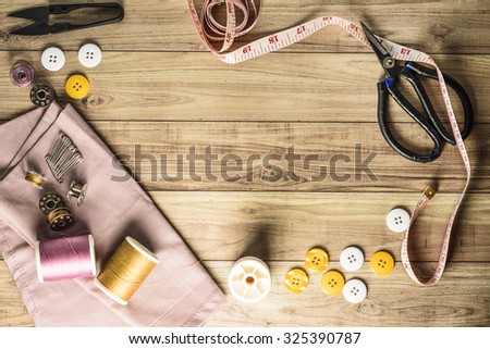 Sewing tools and sewing kit on wooden textured background
