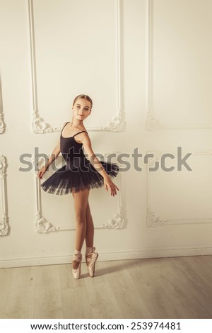 yang lady posing in the studio. Background is white wall. She is in black ballet skirt wearing. She smiles.