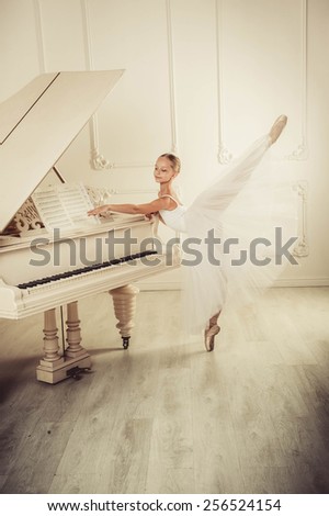 Ballet dancer is dancing in the white hall. In this room piano is standing