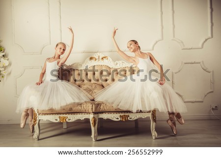 two girls are sitting on the classic sofa . They are ballet dancers.