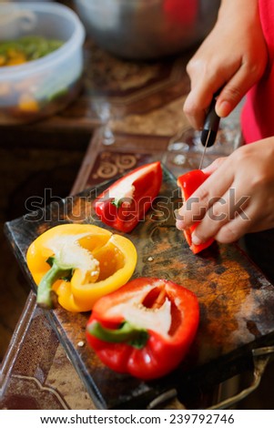 female\'s hand cutting big chili pepper for making food