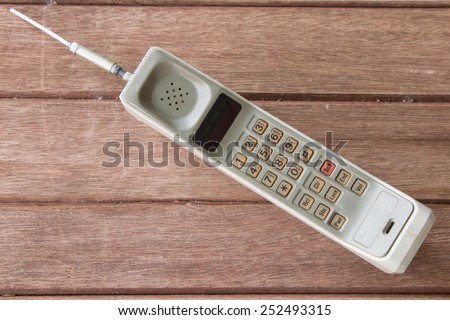 vintage mobile phone on brown wood  background.