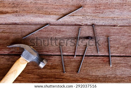 Hammer with nail put on brown wooden table