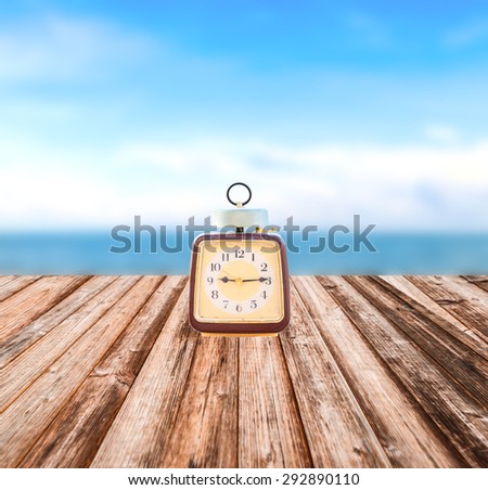 Summer Time, Vintage clock put on wooden with Blurred image of peaceful sea background.