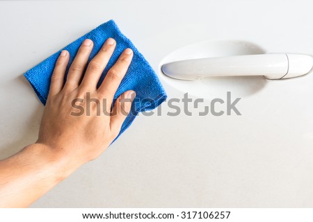 Close up male hand with blue microfiber cloth cleaning the car