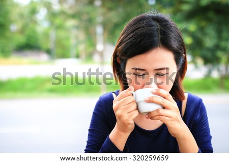 Smile asian woman holding cup of coffee with nature background.