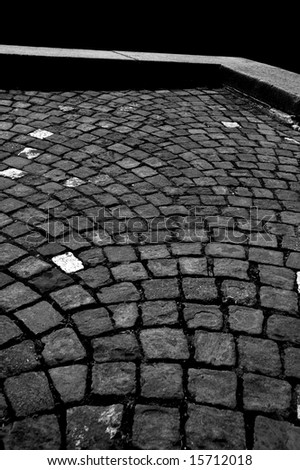 High contrast gray scale picture of an old stone pavement and a stone curb
