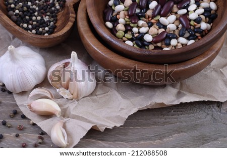 Haricot, lentil and garlic in wooden ware against crushed paper