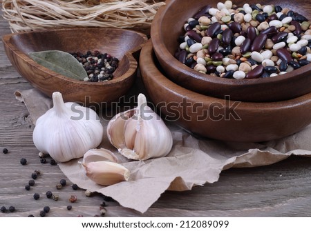 Haricot, lentil and garlic in wooden ware against crushed paper